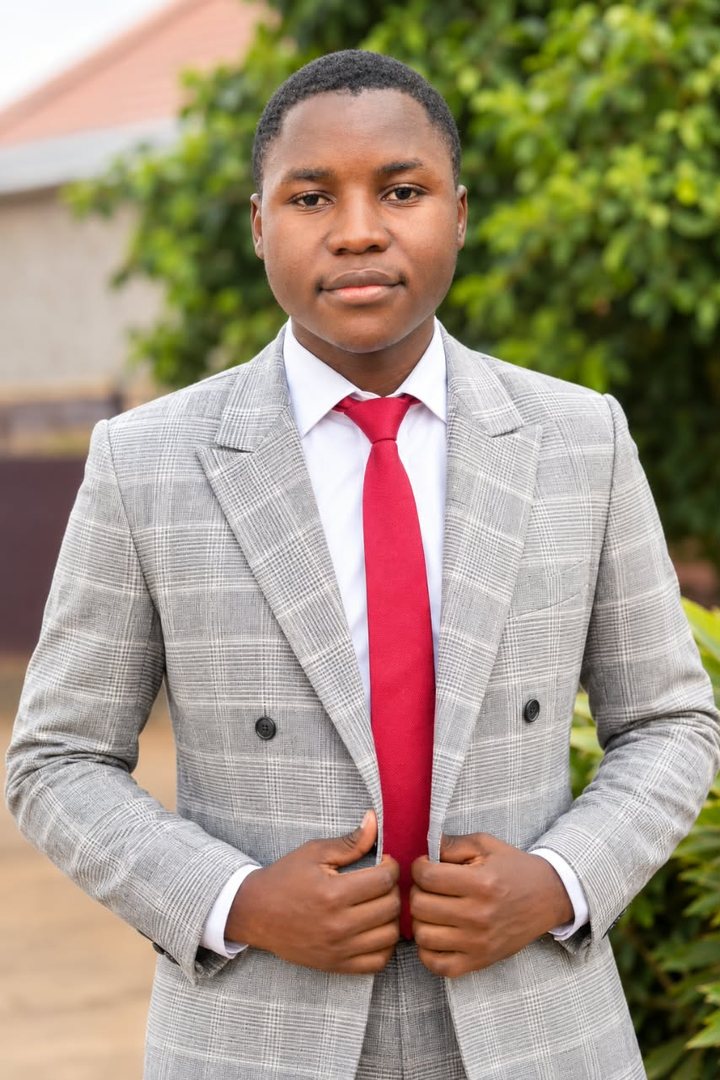 Portrait of Richemond Jagoum in a grey checked suit and red tie